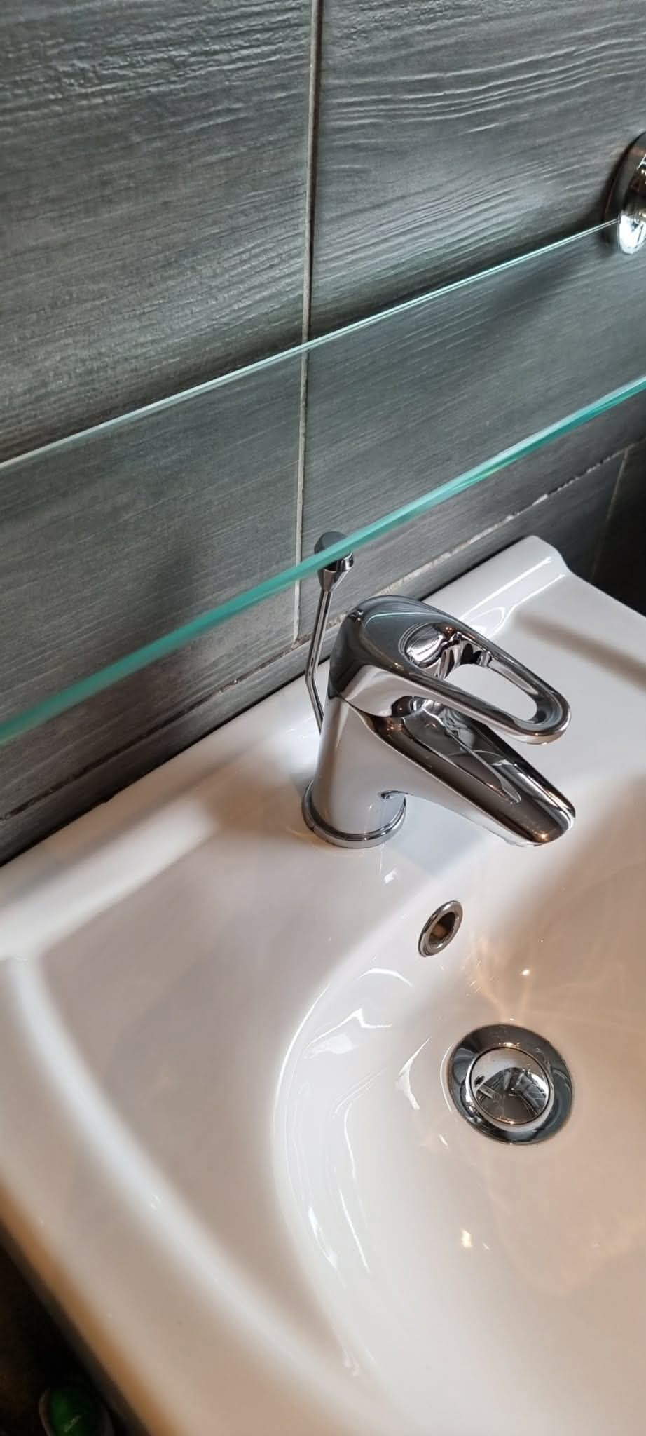 Bathroom basin, tap and glass shelf after cleaning